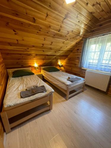 a bedroom with two beds in a wooden cabin at Domki całoroczne - u Ptaka - Miłków in Miłków