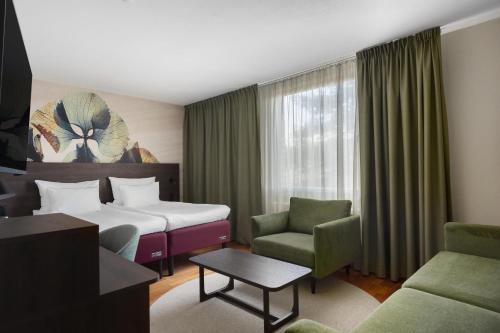 a hotel room with two beds and a chair at Best Western Plus Skogshöjd in Södertälje