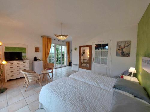 a bedroom with a white bed and a kitchen at Le Clos des 4 Saisons in La Rochepot