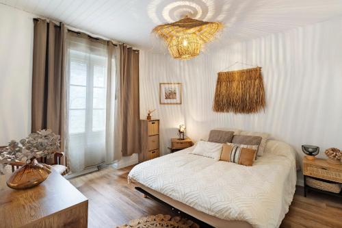 a bedroom with a bed and a chandelier at Le Cocon d'Eymet village in Eymet