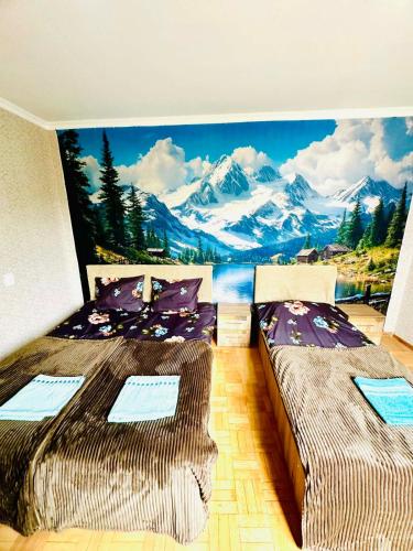 two beds in a room with a mountain mural on the wall at Budget Home in Kutaisi