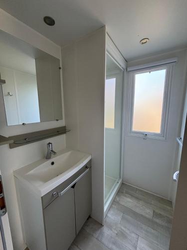 a white bathroom with a sink and a window at Luberon Detente Mobile Home in Cheval-Blanc