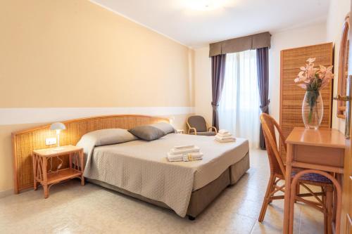 a bedroom with a bed and a table and a vase of flowers at Rina Sea Apartments in Alghero