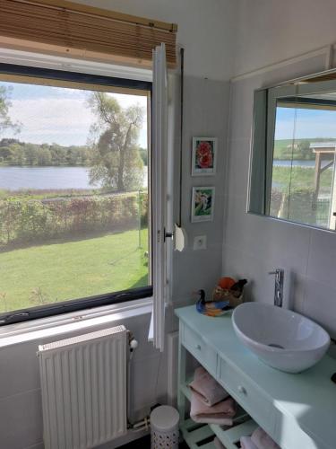a bathroom with a sink and a large window at maison caroline bairon in Le Chesne