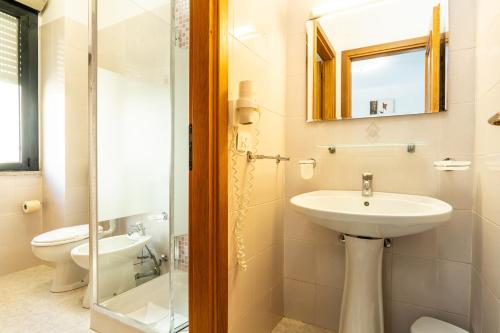 a bathroom with a sink and a toilet and a mirror at Rina Sea Apartments in Alghero