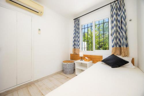 a bedroom with a white bed and a window at Cel Pins in Portopetro