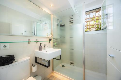 a white bathroom with a sink and a shower at Cel Pins in Portopetro