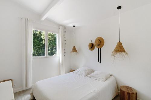 a white bedroom with a bed and a window at Mer et montagne à Conca in Conca