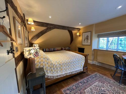 a bedroom with a bed and a table and a window at Under The Thatch at Rose House in Iwerne Minster