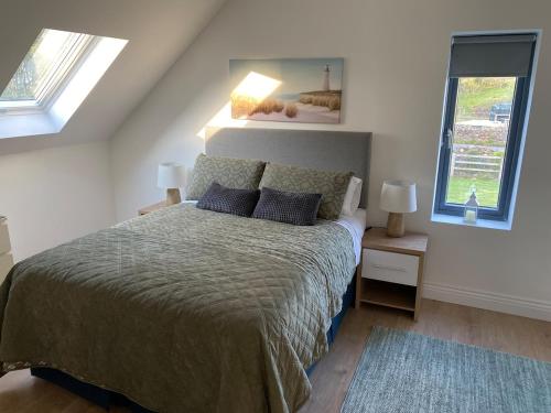 a bedroom with a large bed with two windows at The Stables Apartment in Midleton