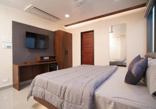 a bedroom with a large bed with a tv on the wall at Sri Rama Grand in Chilakalūrupet