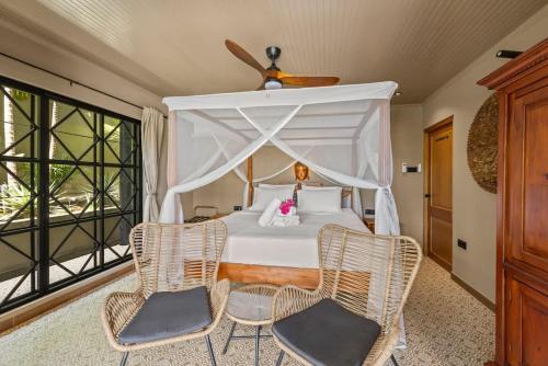 a bedroom with a white bed with two chairs at Bali Suites - Ubud Suite in Willemstad