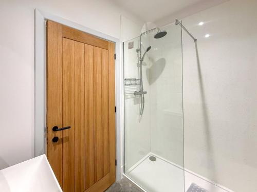 a bathroom with a shower and a wooden door at 4 Bed in Acton oc-k40259 in Waldingfield