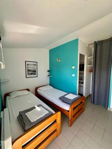 a bedroom with two beds and a blue wall at Le Relais Côtier in Sauzon