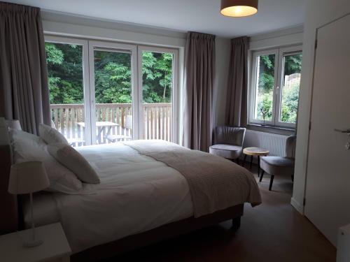 a bedroom with a bed and a balcony with windows at Chalet Du Mont in Ruien