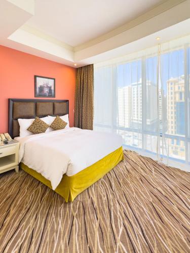 a bedroom with a large bed and a large window at Plazza In Hotel in Doha