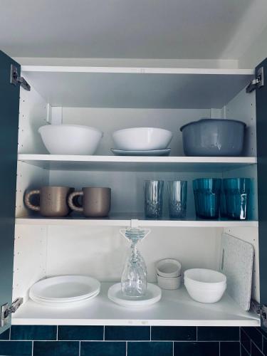a shelf filled with bowls and plates and a vase at Apartament u Liska in Rumia