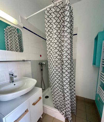 a bathroom with a sink and a shower curtain at Le Relais Côtier in Sauzon