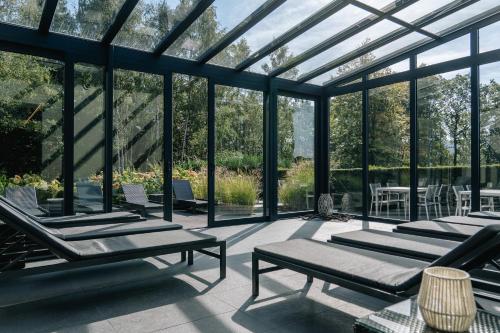 a glass conservatory with lounge chairs and a table at Manoir de Lébioles in Spa