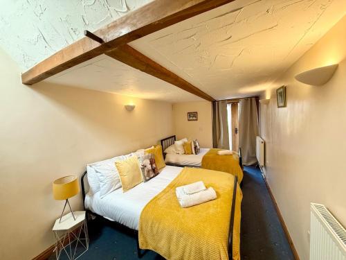 two beds in a small room with yellow sheets at Very spacious rural 2 bed barn sleeps 5 in Usk