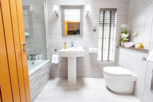 a white bathroom with a sink and a toilet at Grand Fir Lodge - The Hollies Retreats in Tarporley
