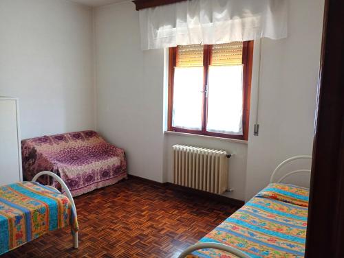 a room with two beds and a window at Appartamento Ginetto in Corsalone
