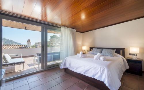 a bedroom with a large bed and a balcony at Luxury Rocamar – Primera Línea y Terraza in Tossa de Mar