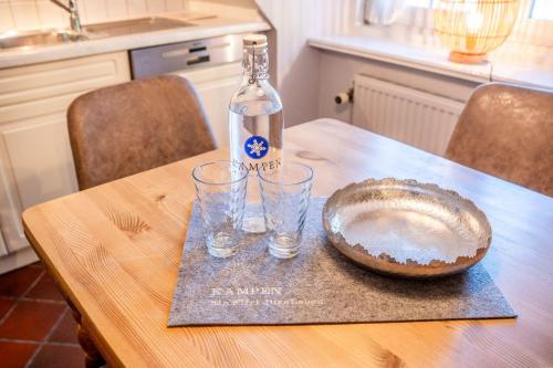 a bottle and two glasses on a wooden table at Haus-Margarete-Nordwind in Kampen