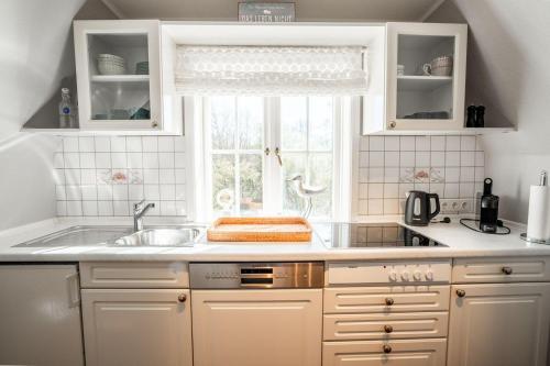 a kitchen with white cabinets and a sink and a window at Haus-Margarete-Westwind in Kampen
