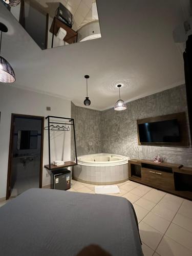 a bedroom with a tub and a tv and a bed at Gran Luha Motel, Hotel in Brotas