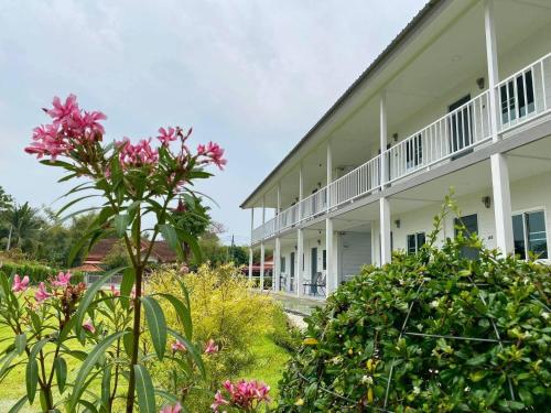 a white building with pink flowers in front of it at กบอุทัย รีสอร์ท in Ban Don Khwang