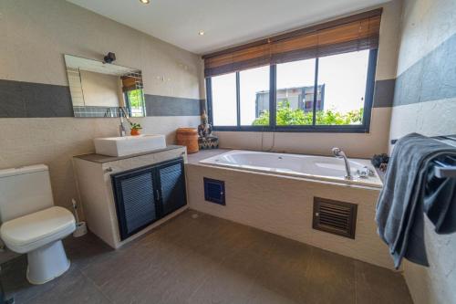 a bathroom with a tub and a toilet and a sink at Malee Beach F1 in Phra Ae beach
