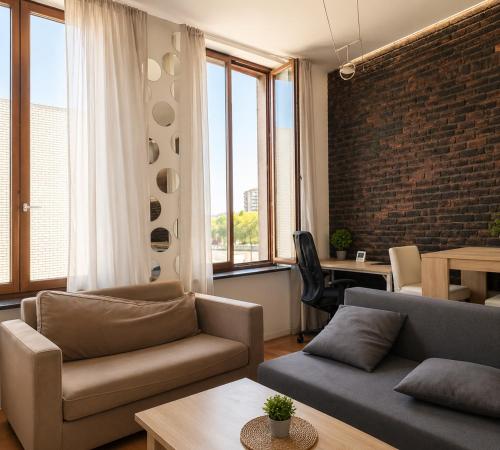 a living room with a couch and a brick wall at Appartement bien-être in Liège