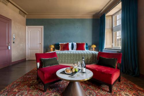 a bedroom with a bed and two red chairs and a table at Manoir de Lébioles in Spa