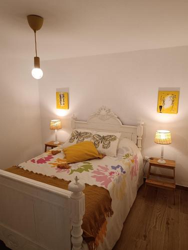 a bedroom with a white bed with a yellow pillow and two lamps at Casa da Lameira in Vilar do Ruivo