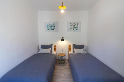 two beds in a room with blue sheets at Agapito's Houses in Praia de Odeceixe