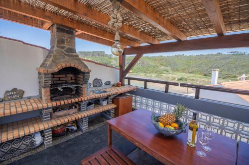 a balcony with a table and an outdoor oven at Agapito's Houses in Praia de Odeceixe