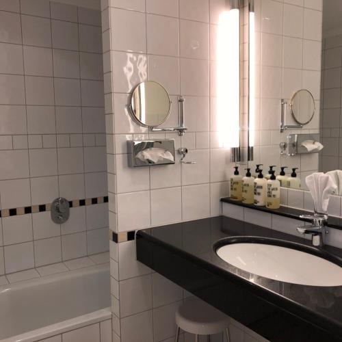 a bathroom with a sink and a tub and a mirror at Hotel Scherf Residenz in Bad Lippspringe