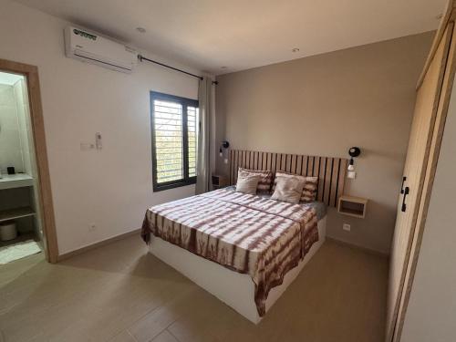 a bedroom with a bed and a window in it at Keur Noflaye Ngaparou in Mbour