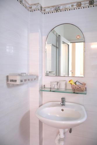 a white bathroom with a sink and a mirror at Xuan Luom Guesthouse in Phan Thiet