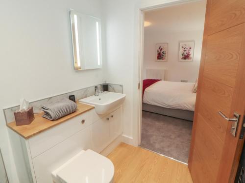 a white bathroom with a sink and a bed at Little Plumtree in Milnthorpe