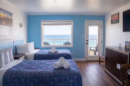 a hotel room with two beds and a balcony at Blue Heron Motel in Nags Head