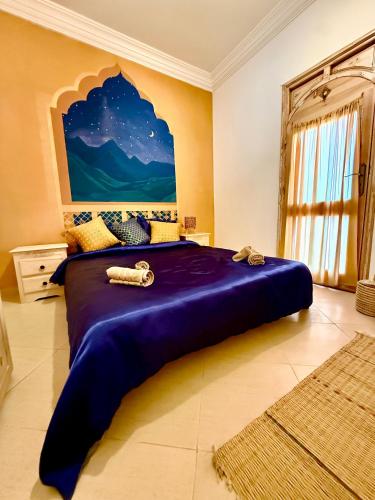 a bedroom with a large purple bed with a painting on the wall at SeArt Home by the Ocean in Aourir