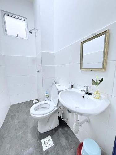a white bathroom with a toilet and a sink at Nj Guesthouse in Tawau