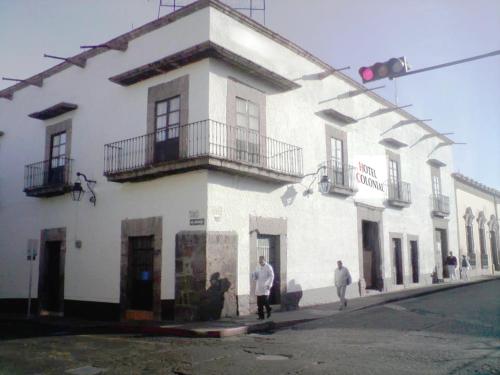 a white building with people walking in front of it at Hotel Colonial in Morelia