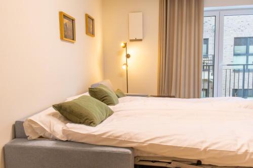 a bed with white sheets and green pillows in a room at Hyggehuus Tossens - Küste33 41 in Tossens