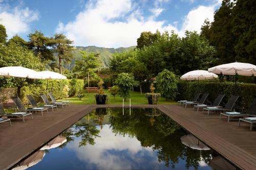 a pool with chairs and umbrellas in a garden at Octant Furnas in Furnas