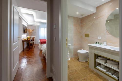 a bathroom with a sink and a toilet and a bedroom at Hotel&Ristorante Miramonti Palazzo Storico in Rieti