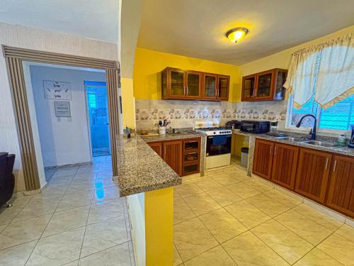 a large kitchen with yellow walls and wooden cabinets at Residential Jula in Los Prados
