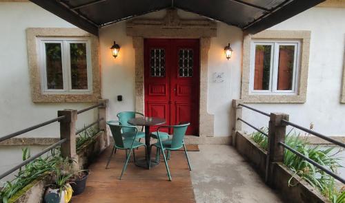 a porch with a red door and chairs and a table at Casa das Essências, Quinta de Santo António in Covilhã